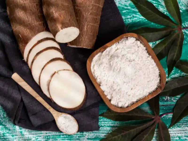 Sliced Benue yam next to a wooden bowl of pounded yam flour